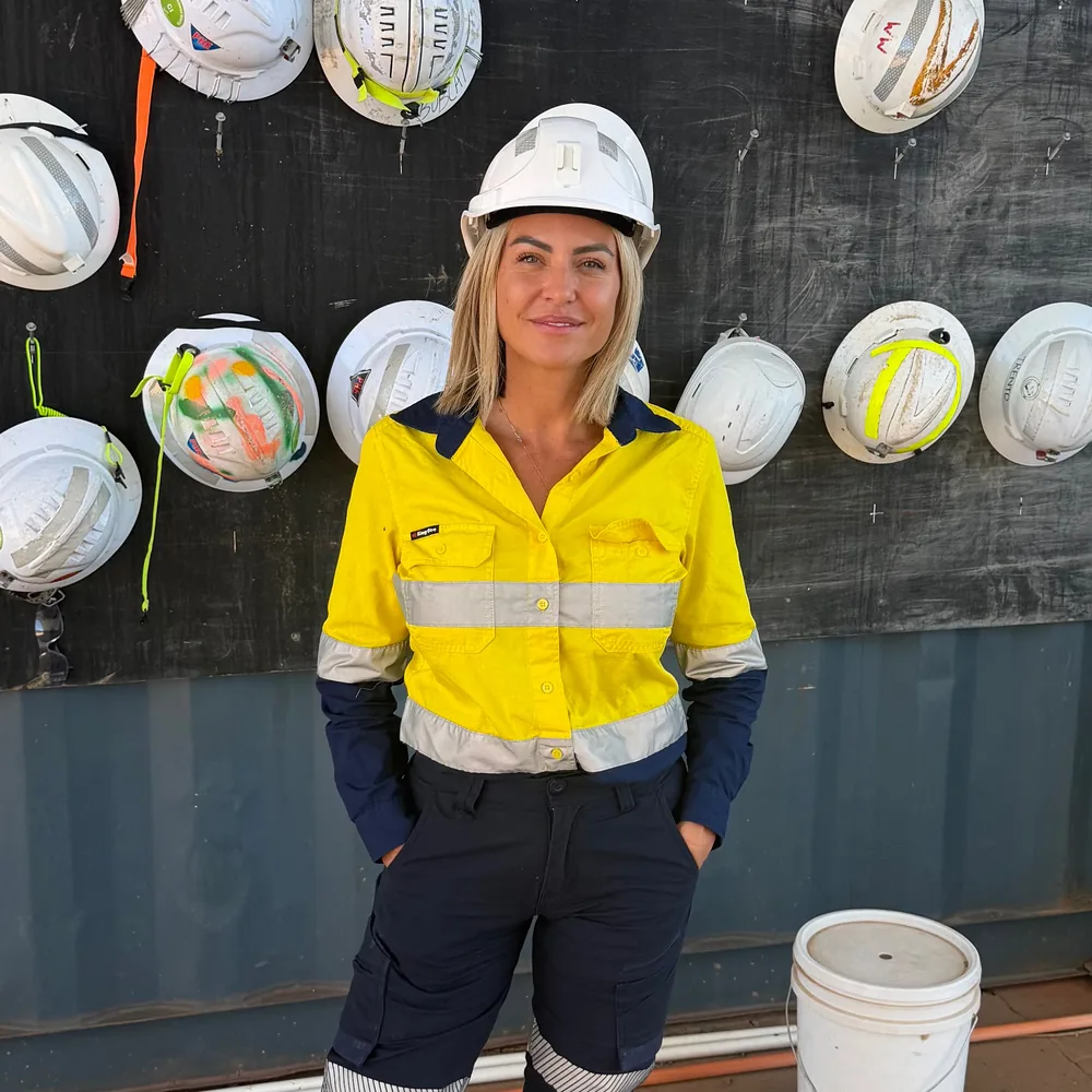Justine Youl in hi-vis and hard hat in front of a site hard hat board